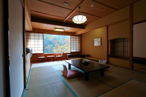 a room with a table and chairs and a large window at Shima Grand Hotel in Nakanojo