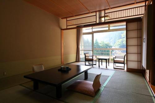 a living room with a table and a balcony at Shima Grand Hotel in Nakanojo