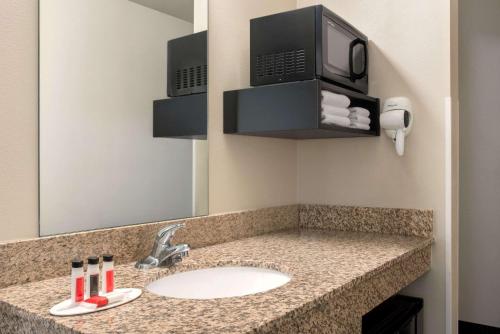 a bathroom with a sink and a microwave at Baymont by Wyndham Glenwood in Glenwood