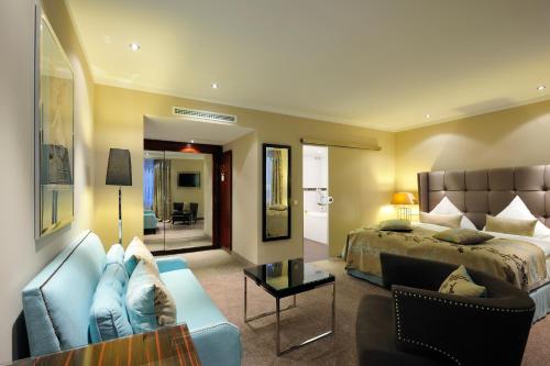 a bedroom with a bed and a couch and a living room at Kastens Hotel Luisenhof in Hannover