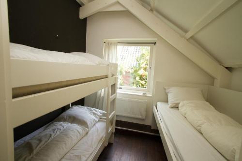 two bunk beds in a room with a window at Koeienstal, Private House with wifi and free parking for 1 car in Weesp