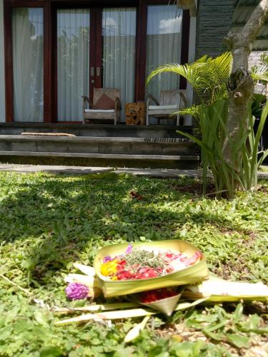 a bowl of flowers on the grass in front of a house at Guest House Reisya in Nusa Dua