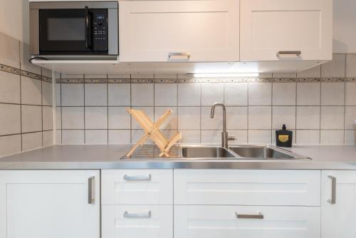 una cucina con armadi bianchi e lavandino di Appartement cœur de ville - Wifi - Lave-sèche linge a Pau