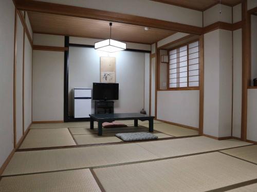 Kimatsu Ryokan في هيروشيما: غرفة فيها تلفزيون وطاولة فيها