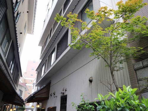 a white building with a tree on the side of it at Kimatsu Ryokan in Hiroshima