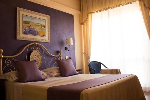 a bedroom with a bed with purple walls and a window at Hotel Ristorante Tre Stelle in Montepulciano