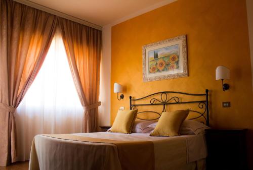 a bedroom with a bed with yellow walls and a window at Hotel Ristorante Tre Stelle in Montepulciano