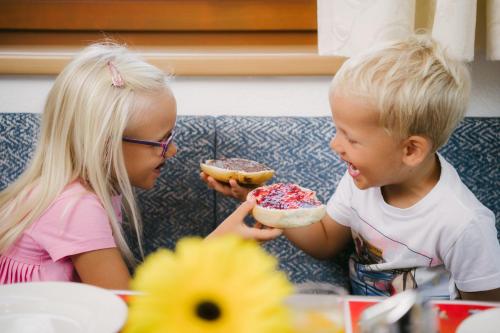two children sitting on a couch eating donuts at Kinderhotel Laderhof in Ladis