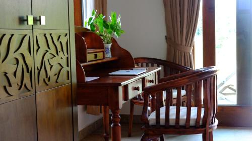 
a wooden table topped with a chair next to a window at Villa Cathaya - Private Pool in Pantai Cenang
