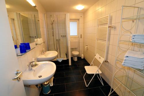 a bathroom with two sinks and a shower and a toilet at Ferienwohnungen Schmider in Rust