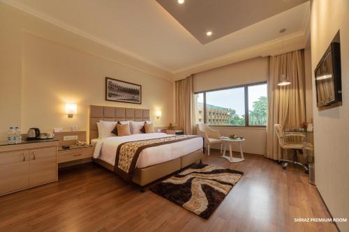 a hotel room with a bed and a large window at Hotel Clarks Shiraz in Agra
