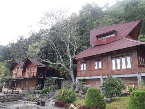 a large wooden house in front of a mountain at Pondok Berata Dapdap in Balige