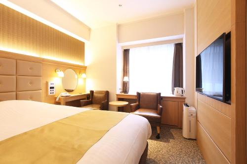 a hotel room with a bed and a television at Kobe Luminous Hotel Sannomiya in Kobe