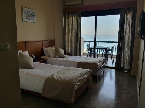 two beds in a hotel room with a view of the ocean at Holiday Suites Hotel & Beach Resort in Jounieh