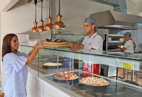a woman is holding a tray of food in a kitchen at San Francesco Camping Village in Desenzano del Garda