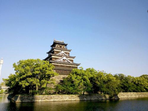 a pagoda towering over a body of water with trees at Kimatsu Ryokan in Hiroshima