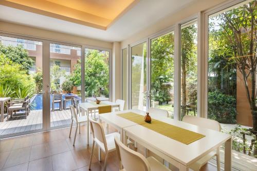 a dining room with large windows and white tables and chairs at U Tiny Boutique Hotel Suvarnabhumi Bangkok - SHA Plus in Lat Krabang