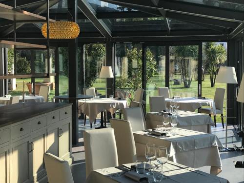 a restaurant with white tables and white chairs and windows at Hotel Albergo Villa Marta in Lucca