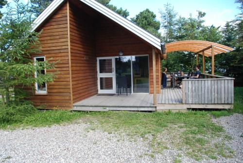 a log cabin with a deck and a patio at Hytteby – Hanstholm Camping – Thy Feriepark in Hanstholm