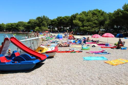 a group of people on a beach with boats at Apartments Maria in Tisno