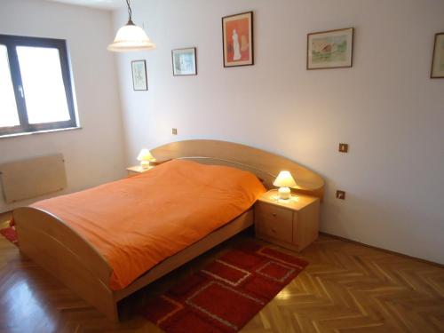 a bedroom with a bed with an orange blanket and two lamps at Apartment Gioia in Savudrija