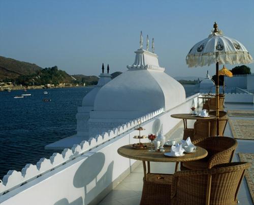 a balcony with tables and chairs and the water at Taj Lake Palace Udaipur in Udaipur