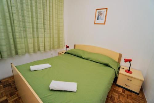a bedroom with a green bed with two towels on it at Apartment Mandica in Savudrija