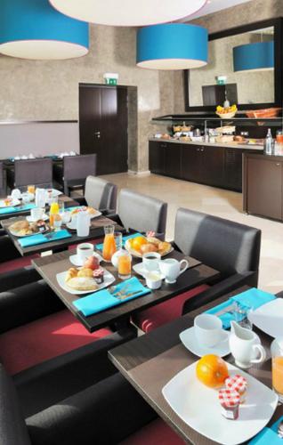 a dining room with tables and chairs with food on them at Residhome Nantes Berges De La Loire in Nantes