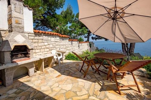 a table and chairs with an umbrella next to a stone fireplace at Villa Ana in Savudrija