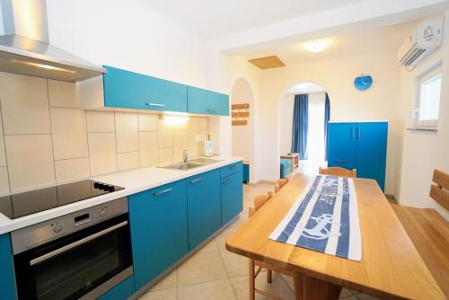 a kitchen with blue cabinets and a wooden table at Apartment Nino Savudrija in Bašanija