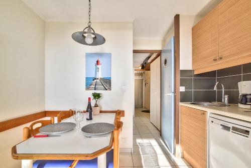 a kitchen and dining room with a table and a lighthouse at Appartement l'Archipel - Vue mer exceptionnelle et bassins aquatiques du 29 avril au 15 sept in Talmont