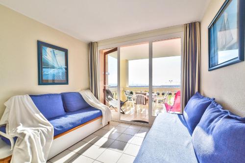 a living room with a blue couch and a balcony at Appartement l'Archipel - Vue mer exceptionnelle et bassins aquatiques du 29 avril au 15 sept in Talmont