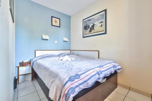 a small bedroom with a bed with blue walls at Appartement l'Archipel - Vue mer exceptionnelle et bassins aquatiques du 29 avril au 15 sept in Talmont