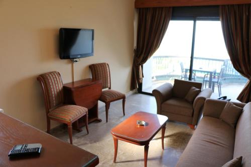a living room with a couch and chairs and a tv at Holiday Suites Hotel & Beach Resort in Jounieh