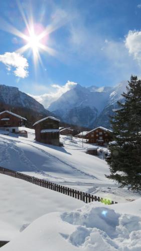 a snow covered mountain with the sun in the sky at Chalet Safran in Grächen