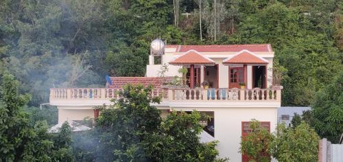 a white house with a balcony on top of it at NGO KHANH Homestay in Tân Hiệp