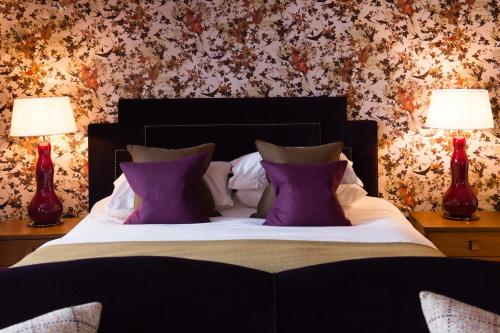 a bedroom with a bed with purple pillows and two lamps at One Devonshire Gardens a Hotel Du Vin in Glasgow