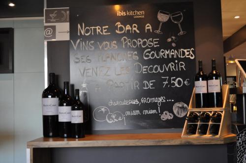 a chalkboard with a bunch of wine bottles on a shelf at ibis Avignon Centre Gare in Avignon