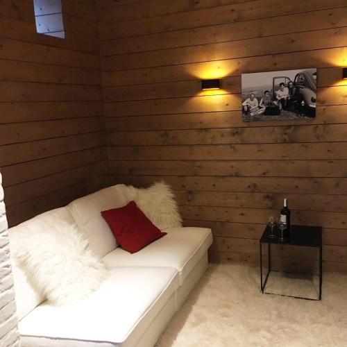 een kamer met een witte bank in een houten muur bij Le Nid in Manhay