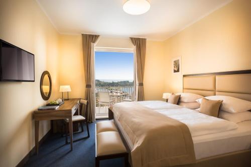 a hotel room with a bed and a desk and a window at Remisens CASA ROSA - Hotel Metropol Annexe in Portorož
