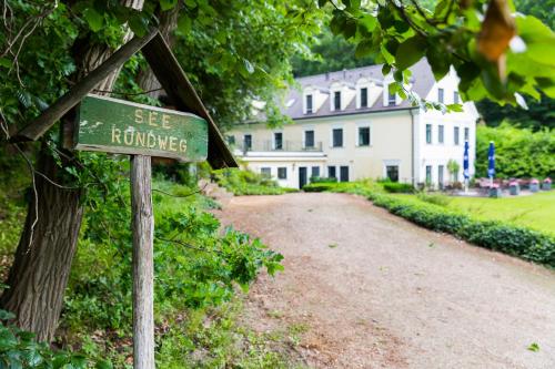 a green street sign in front of a building at Hotel Gut Klostermühle natur resort & medical spa in Alt Madlitz