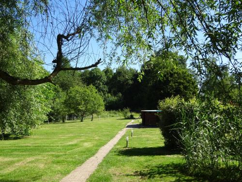 a path in a park with trees and a building at Les chaumières du Chêne in Pouillé