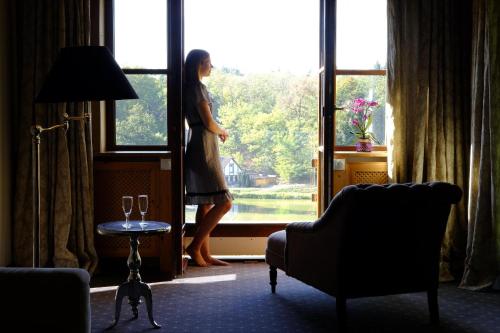 a woman standing in a window looking out at Hotel Gut Klostermühle natur resort & medical spa in Alt Madlitz