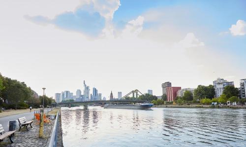 a river with a bridge and a boat on it at Living Hotel Frankfurt in Frankfurt/Main