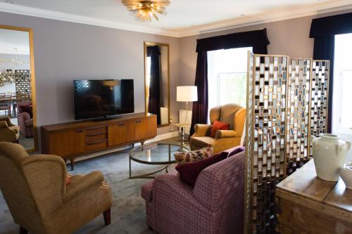 a living room with a tv and a couch and chairs at One Devonshire Gardens a Hotel Du Vin in Glasgow