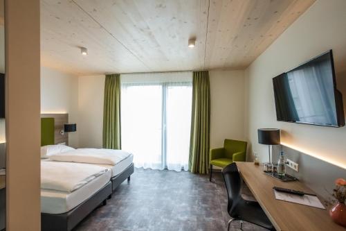 a hotel room with two beds and a desk and a tv at Hotel Holzscheiter in Lottstetten