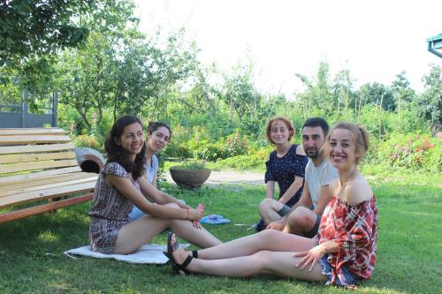 a group of people sitting in the grass at Guesthouse Alvani in Nizhniy Alvani