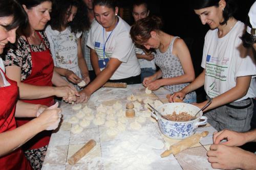 a group of people standing around a table playing chess at Guesthouse Alvani in Nizhniy Alvani
