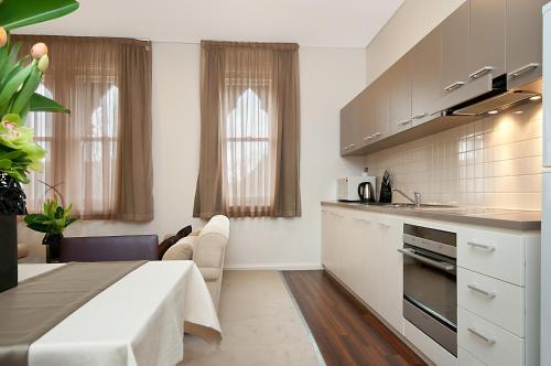 uma cozinha com armários brancos e uma sala de jantar em Adabco Boutique Hotel Adelaide em Adelaide