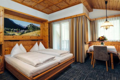 um quarto de hotel com duas camas e uma mesa em Wellnesshotel Engadin em Samnaun